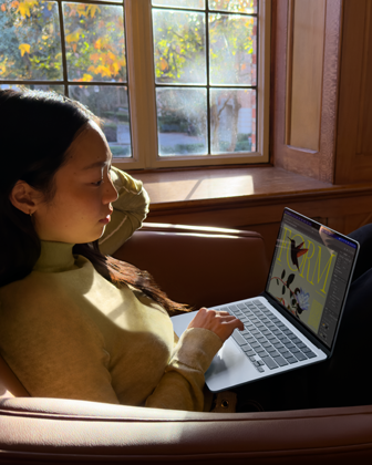 椅子に座ってMacBook Airを使っている人物